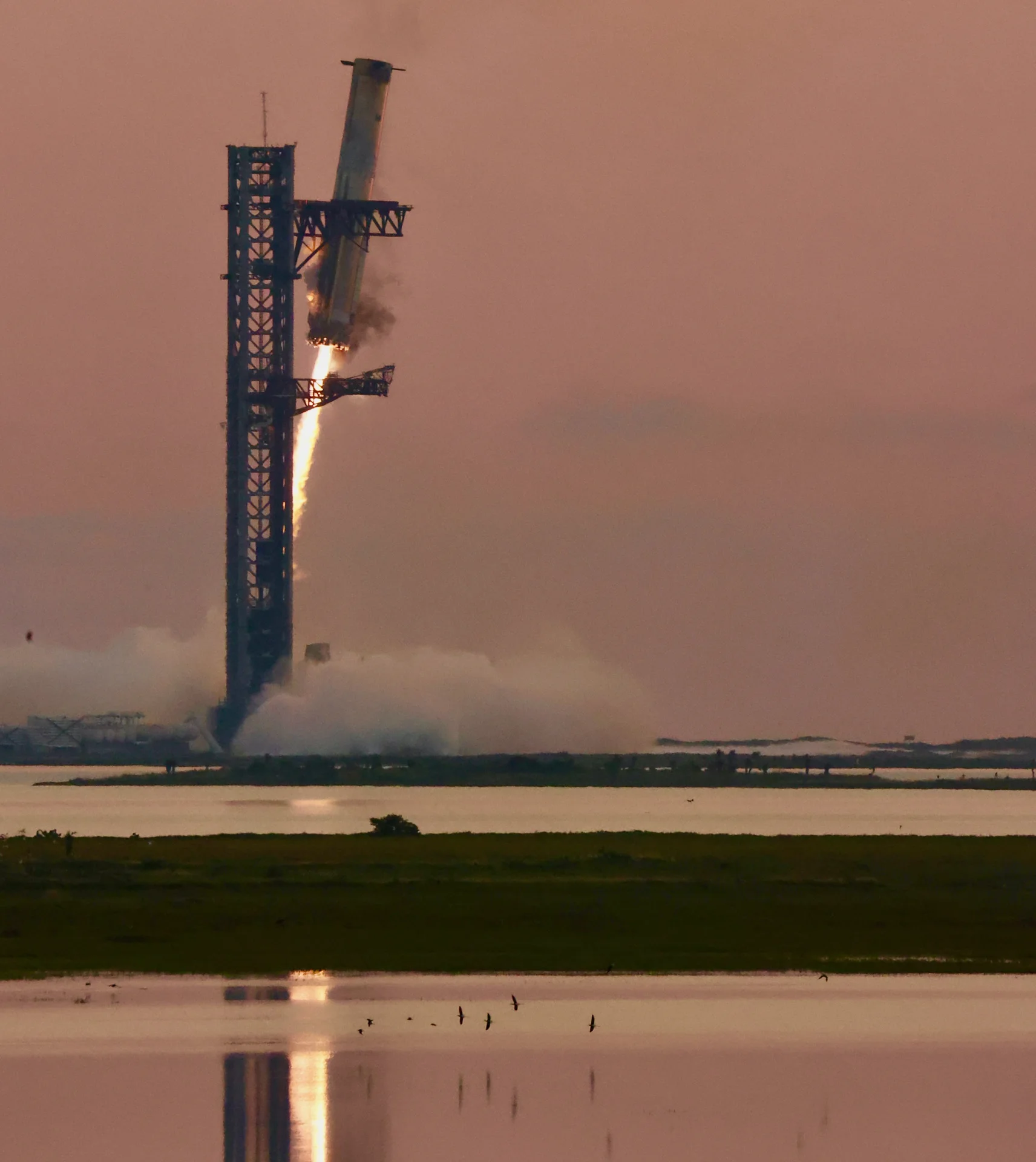 Super Heavy descends beside the Starbase launch tower during Flight 5.